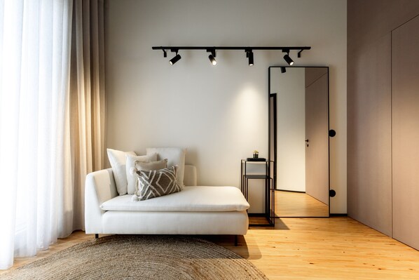 Un salon moderne avec un canapé, un miroir et un plancher en bois.