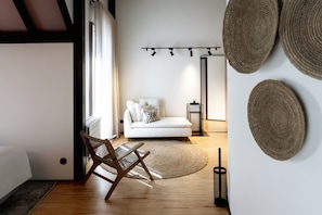 Een moderne woonkamer met een witte bank, een geweven vloerkleed en een houten vloer.