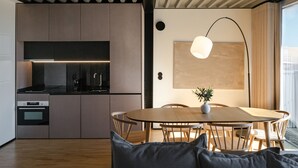 Una cocina moderna con electrodomésticos integrados, un comedor con una mesa redonda y sillas, y una lámpara colgante.