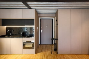 A modern kitchen with built-in appliances, a wooden floor, and a door leading to another room.