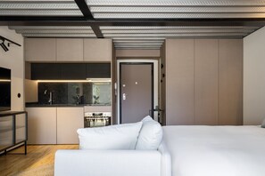 Une chambre d’hôtel moderne dotée d’un grand lit, d’une kitchenette et offrant une vue sur l’extérieur.