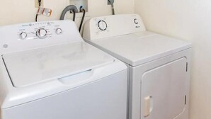 Two white front-loading washing machines in a laundry room with a wooden floor. - Condo Caribbean Dreams (Dangriga)