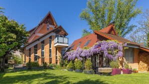 A two-story house with a red-tiled roof, a balcony, and a garden with purple wisteria vines. - Quiet Studio · Full Kitchen · Personal Welcome · Near Basel (Saint-Louis)