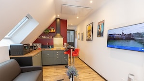 Un appartamento moderno con cucina, zona pranzo e soggiorno. Dispone di un soffitto a volta, una televisione a schermo piatto e opere d'arte alle pareti.