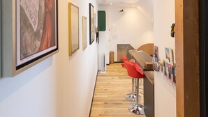 Un corridoio con pavimento in legno, un'area bar con sedie rosse e opere d'arte incorniciate alle pareti.