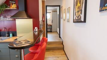 Une cuisine moderne avec un mur d’accent rouge, une hotte de cuisinière en acier inoxydable et un coin bar agrémenté d’un tabouret rouge.