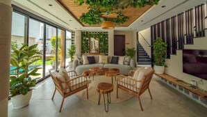 A modern living room with a sofa, round coffee tables, and wicker chairs. - Twin room in Private villa (Dubai)
