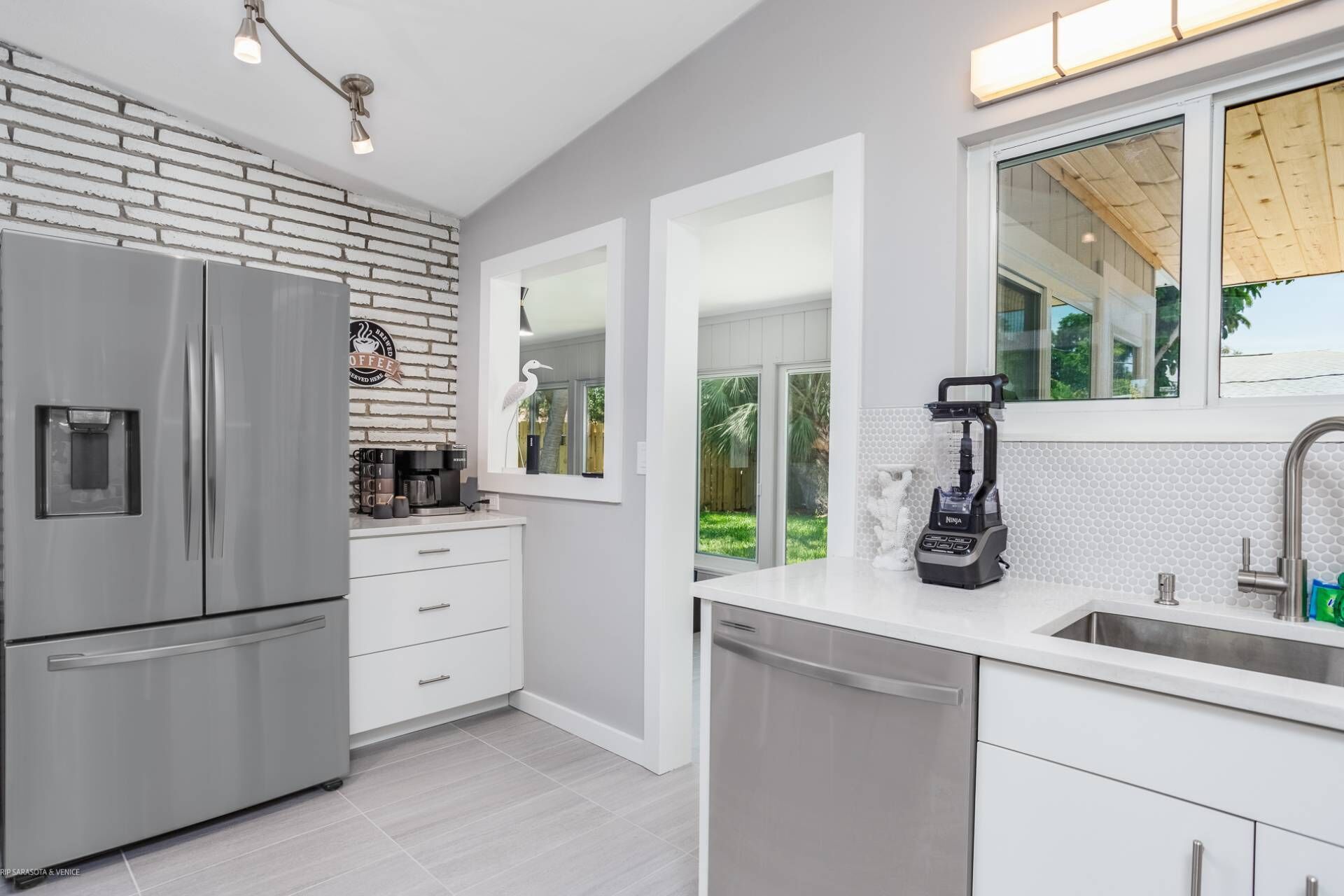 A modern kitchen with a stainless steel refrigerator, a coffee machine, and a dishwasher.