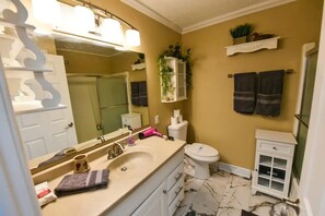 Ein Badezimmer mit Waschbecken, Spiegel, Toilette und einem kleinen Schrank.