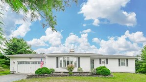 A single-story house with a garage, a front porch, and a small garden area with two bushes. - Whispering Pines Manor

 (Johnstown)