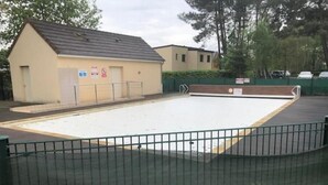 A swimming pool with a fenced area, a small building with a sign, and a parking lot with cars. - Appartement en Résidence Sécurisée Circuit 2kms (Le Mans)