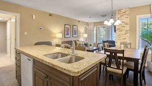 A modern kitchen with granite countertops, a built-in dishwasher, and a dining area with a chandelier. - Beautiful Jacuzzi Suite with Garden View/Studio (Shanty Bay)