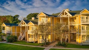 A row of yellow multi-story buildings with balconies, a central walkway, and a well-maintained lawn. - Beautiful Jacuzzi Suite with Garden View/Studio (Shanty Bay)