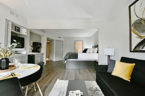 Een moderne hotelkamer met een zithoek, kitchenette en een bed met uitzicht.