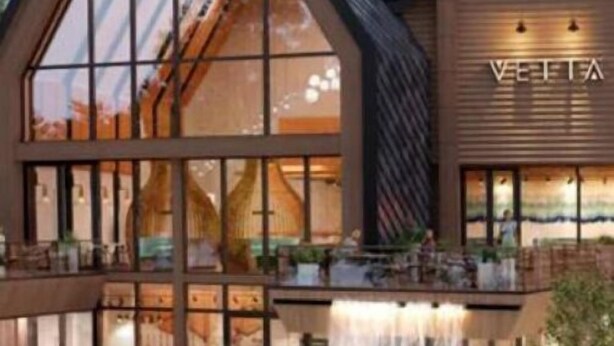 Un hotel moderno con una amplia fachada de vidrio, una cascada y una zona de piscina.