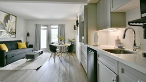 Una cocina moderna con armarios blancos, un lavamanos de acero inoxidable y un lavavajillas negro.
