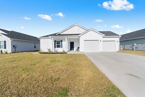 A single-story residential house with a front porch, a garage, and a well-maintained lawn.