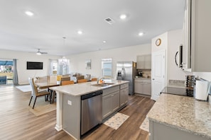 A modern kitchen with a central island, stainless steel appliances, and a dining area with a view.