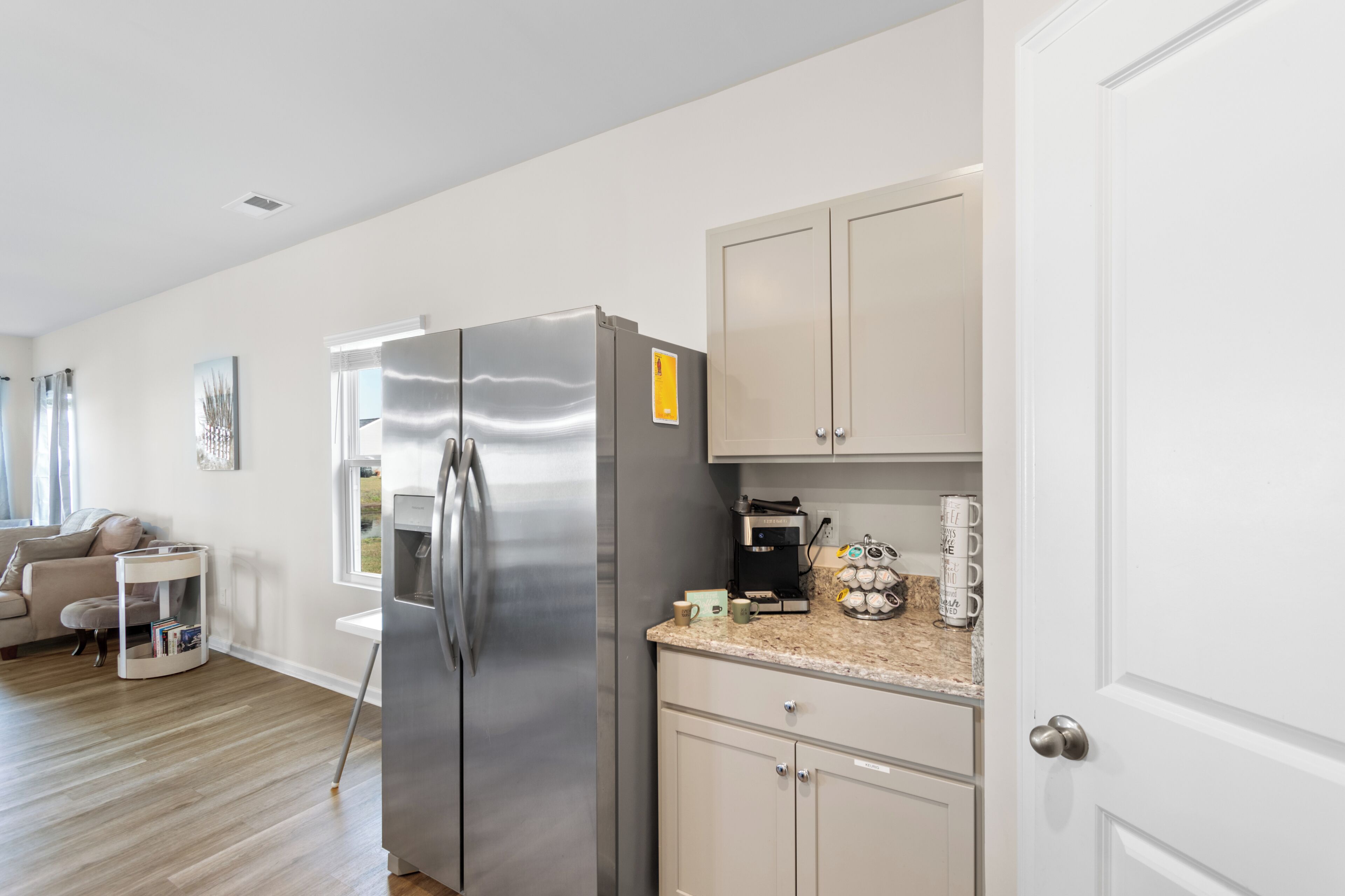 A modern kitchen with a stainless steel refrigerator, a coffee machine, and a countertop with a coffee pot and cups.