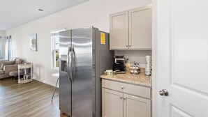 Eine moderne Küche mit einem Edelstahl-Kühlschrank, einer Kaffeemaschine und einer Arbeitsplatte mit Kaffeekanne und Tassen.
