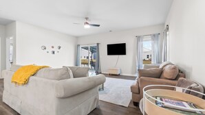 Ein modernes Wohnzimmer mit einem beigen Sofa, einem Couchtisch und einem an der Wand befestigten Flachbildfernseher.