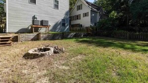 A residential area with two houses, one with a visible air conditioning unit and a fire pit in the yard. - Colington Harbour OBX Cottage (Kill Devil Hills)