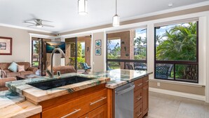 A modern kitchen with a large island, a built-in dishwasher, and a view of the outdoors. - Includes Beach Gear!  134 Shores at Waikoloa (Waikoloa Beach Resort)