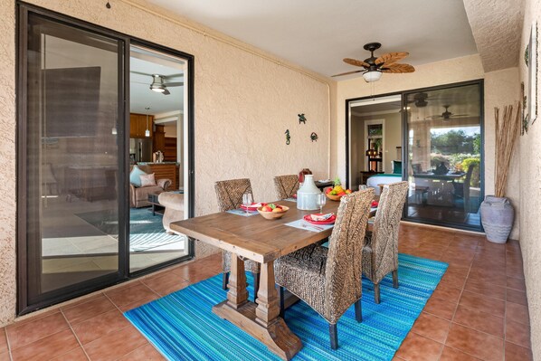 A dining area with a wooden table, patterned chairs, and a blue rug. - Includes Beach Gear! 134 Shores at Waikoloa (Waikoloa Beach Resort)