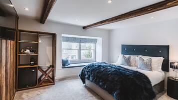 A bedroom with a large bed, a window with a view, a wardrobe, and a small table.