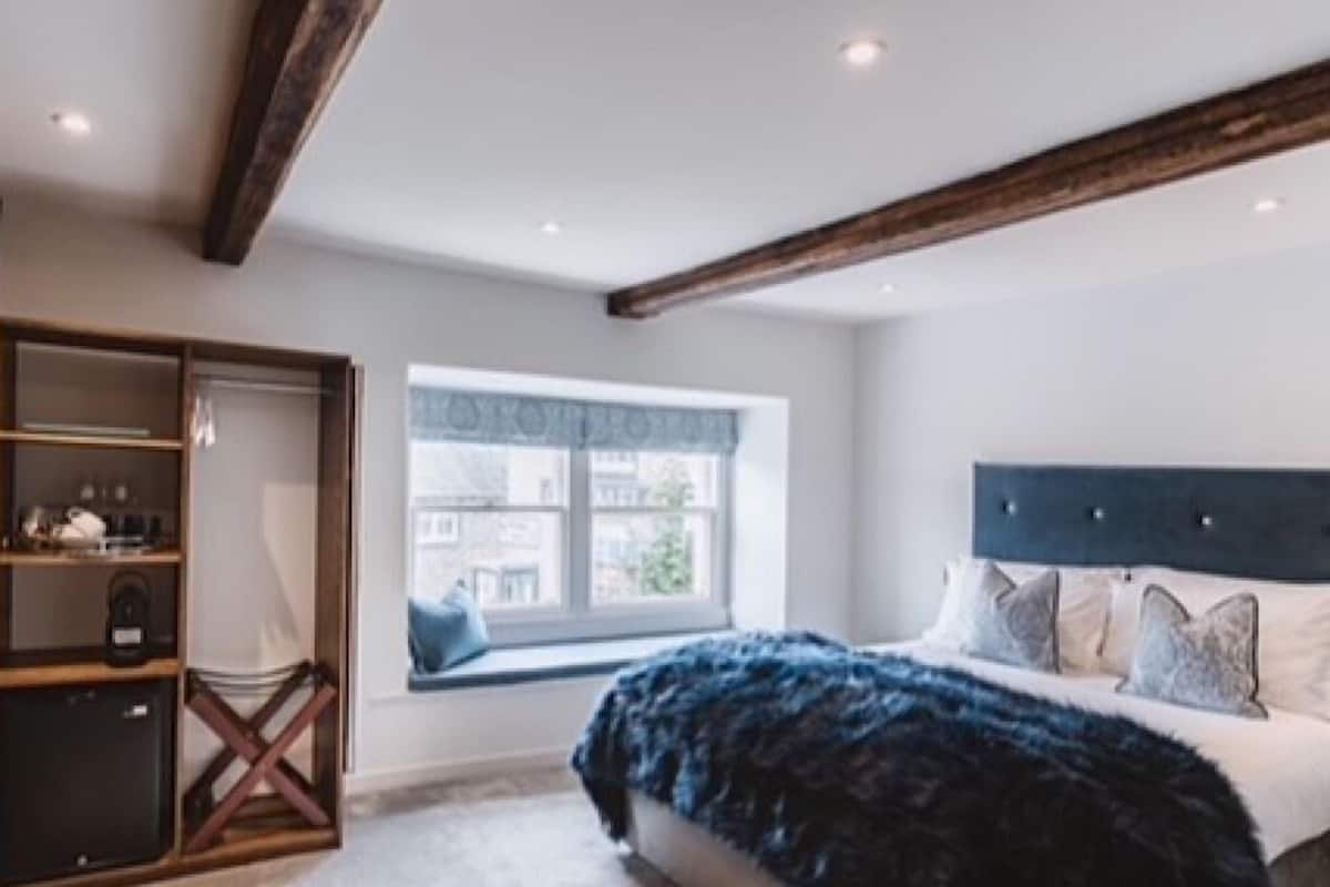 Une chambre dotée d’un grand lit, d’une fenêtre offrant une belle vue, d’une armoire intégrée et d’un plafond avec des poutres apparentes.