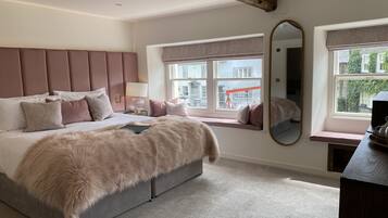 A bedroom with a large bed, a window with a view, a mirror, and a bedside table.