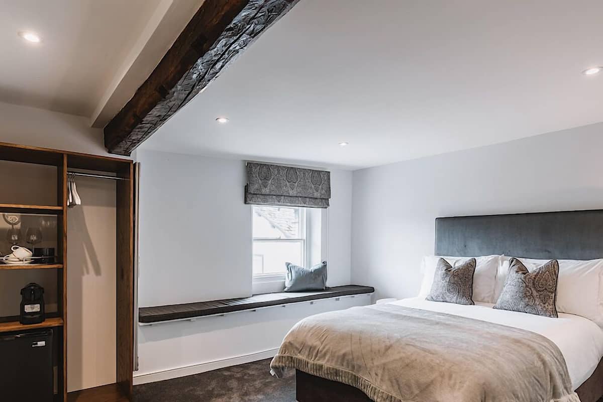 Une chambre avec un grand lit, une fenêtre donnant sur un beau paysage, un banc intégré et une armoire en bois.
