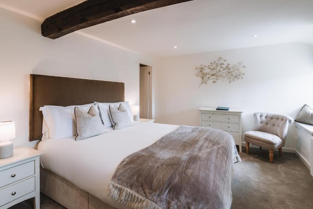 Een slaapkamer met een groot bed, een nachtkastje, een stoel en een dressoir.