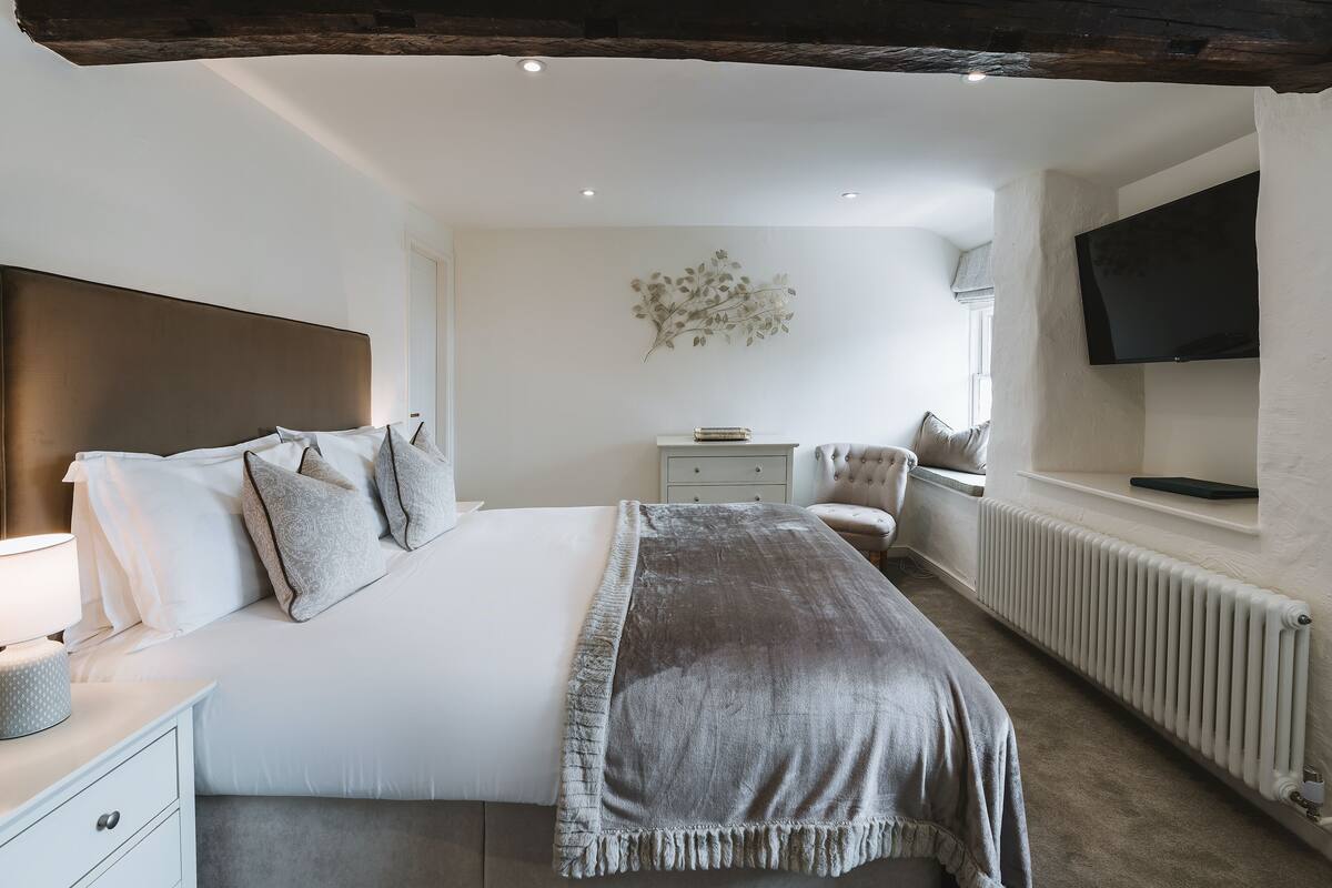 Une chambre moderne avec un grand lit, des tables de chevet, un téléviseur et un radiateur.