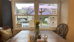 A dining table with a 'Reserved' sign, a vase with yellow flowers, and a menu board in a restaurant with large windows. - Coffee & Stays at Cartmel Square (Grange-over-Sands)