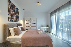 Relax in comfort with a large bed, bedside table, and desk, surrounded by a clean and minimalist design.