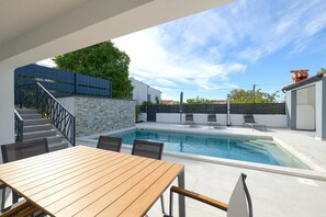 Relax by the pool surrounded by a secure, space with a wooden table and chairs.