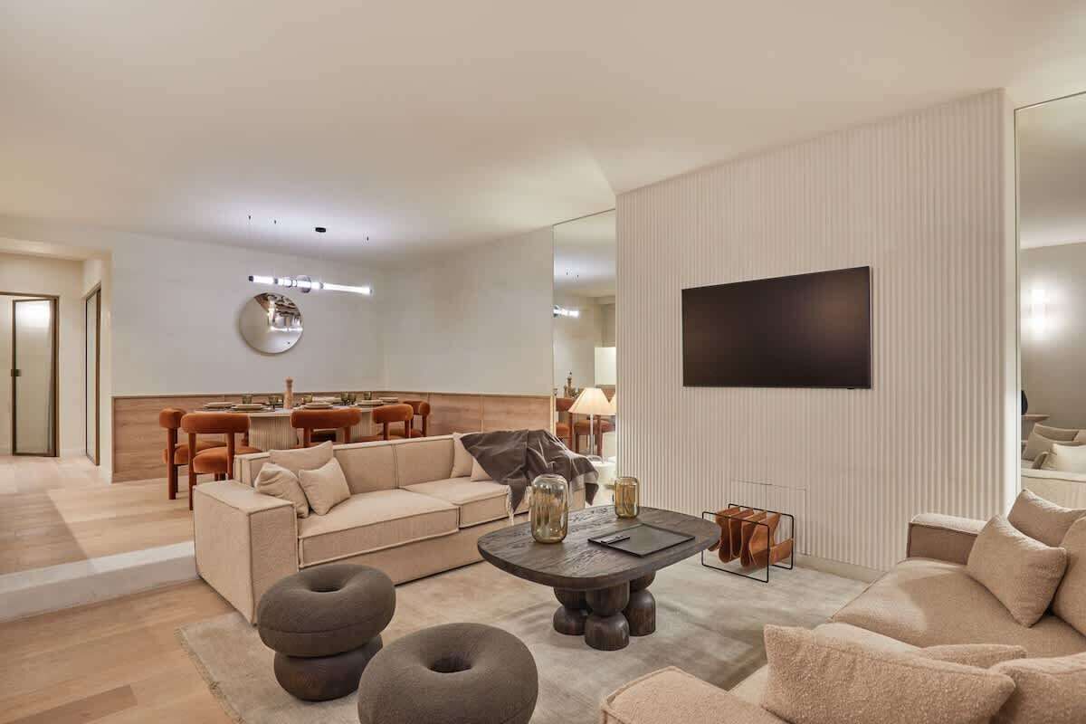 A modern living room with a sofa, coffee table, and a flat-screen TV mounted on the wall.