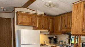 Eine kleine Küche mit Holzausstattung, einem weißen Kühlschrank, einem Herd und einem Spülbecken.
