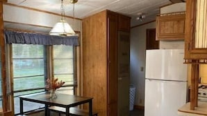 Eine kleine Küche mit Esstisch, Holzschränken und einem Kühlschrank.