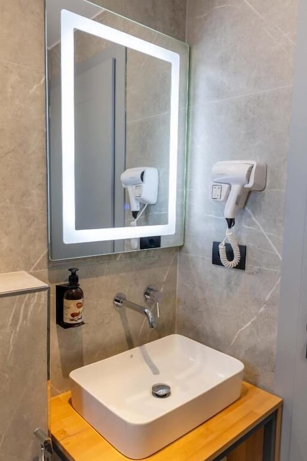 A modern bathroom with a large mirror, a hairdryer, a phone, and a sink. - Resol Hotel 2 (Ksamil)