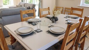 A dining area with a white table set for four, surrounded by wooden chairs. - THE SKATING ROCK, pet friendly in Kenmare, County Kerry (Bonane)