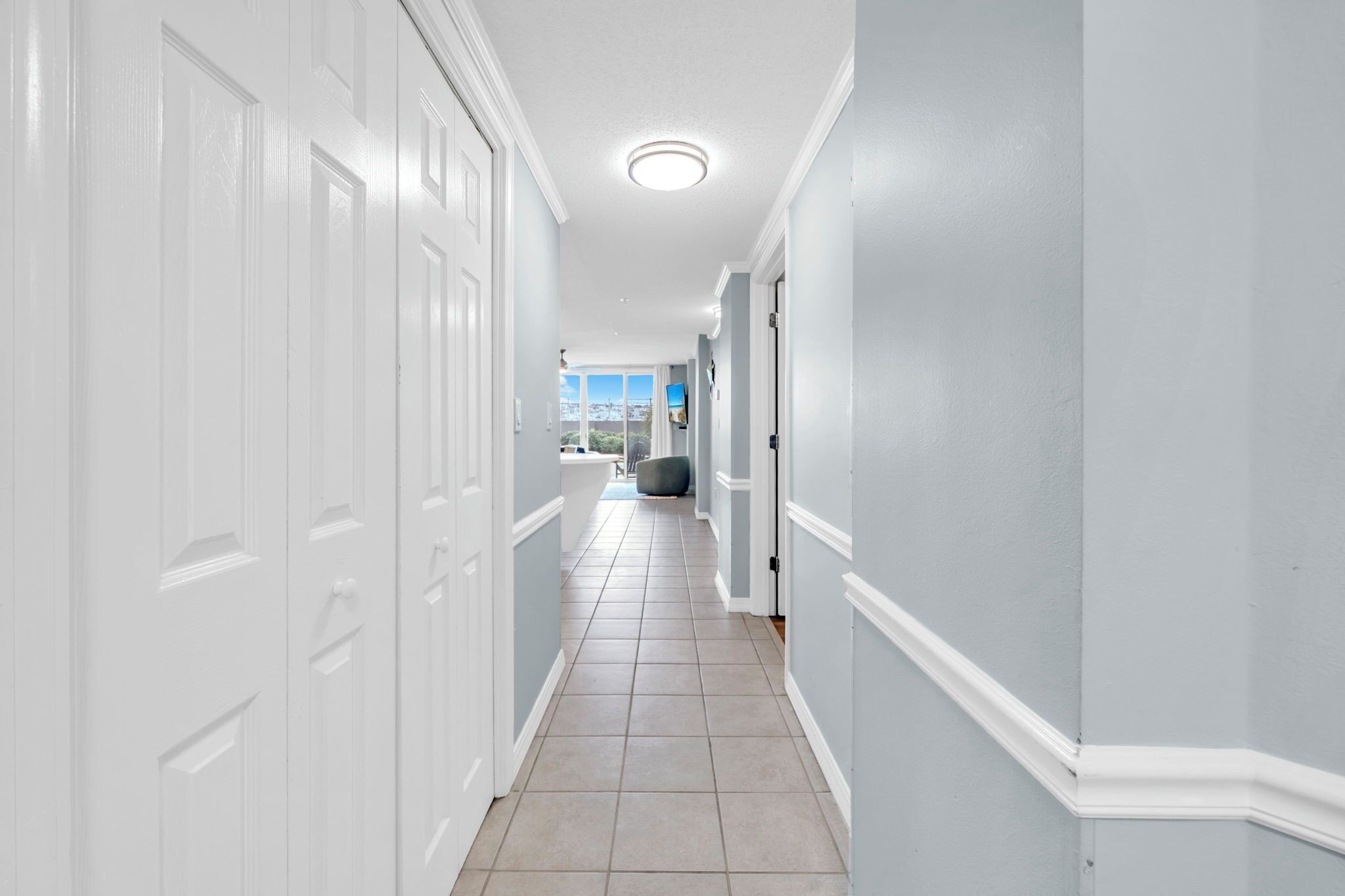 A hallway with white doors, light blue walls, and a tiled floor.