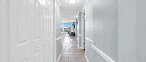 A hallway with white doors, light blue walls, and a tiled floor.