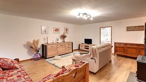 A cozy living room with a wooden bed, a sofa, a TV, and a kitchen area. - La Perle de Xonrupt - Appt vue montagne (Xonrupt-Longemer)