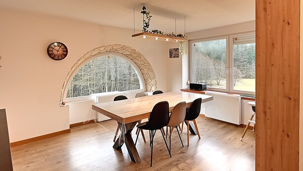 A modern kitchen with a large wooden table, black chairs, a stone arch window, and a hanging plant light fixture. - La Perle de Xonrupt - Appt vue montagne (Xonrupt-Longemer)