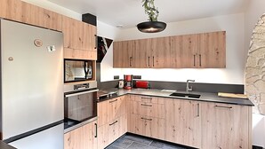 A modern kitchen with wooden cabinets, a stainless steel refrigerator, and a black countertop. - La Perle de Xonrupt - Appt vue montagne (Xonrupt-Longemer)