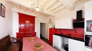 Eine Küche mit kariertem, rot-weißen Tischläufer, einem roten Schrank und einer schwarzen Arbeitsplatte.