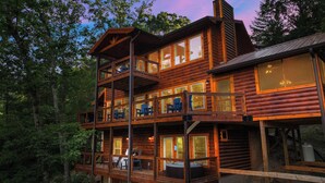 A multi-level log cabin with balconies, large windows, and outdoor seating.