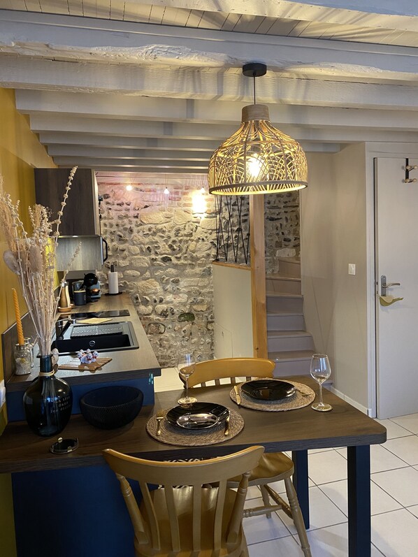Enjoy meals in this charming dining area with a stone wall, wooden beams, and a cozy atmosphere.